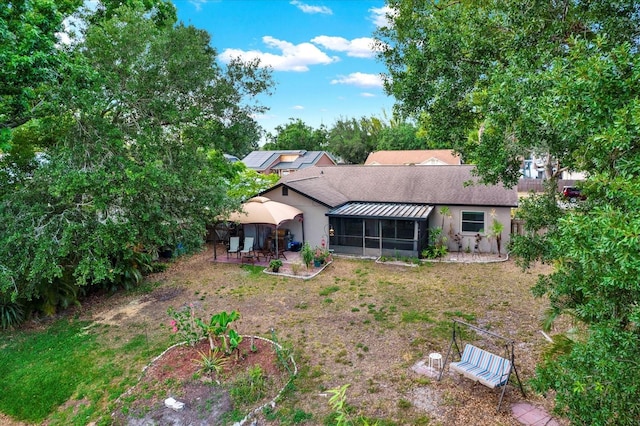 back of property featuring a patio, roof with shingles, stucco siding, a sunroom, and a lawn