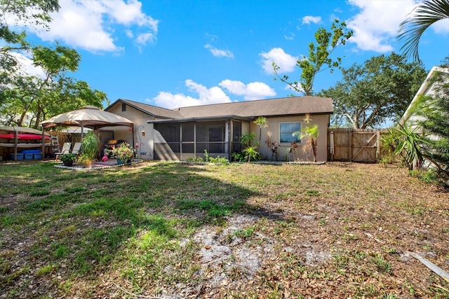 rear view of house with fence, stucco siding, a sunroom, a gazebo, and a yard