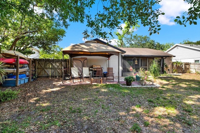back of property featuring a fenced backyard, a patio, a shingled roof, and a sunroom