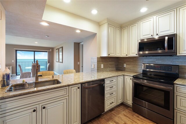 433 Mariner Dr Unit 433, Tarpon Springs, FL 34689 - kitchen featuring appliances with stainless steel finishes, decorative backsplash, light wood-type flooring, and light stone counters