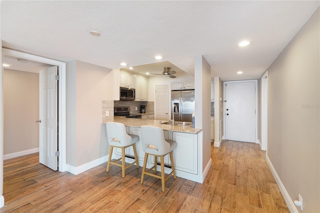 433 Mariner Dr Unit 433, Tarpon Springs, FL 34689 - kitchen with decorative backsplash, a peninsula, baseboards, light wood-style flooring, and stainless steel appliances