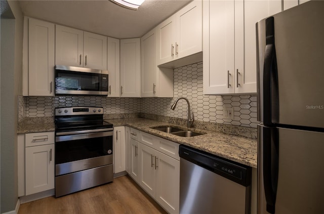 1716 11th Ave N, Saint Petersburg, FL 33713 - kitchen with a sink, stainless steel appliances, decorative backsplash, white cabinets, and wood finished floors