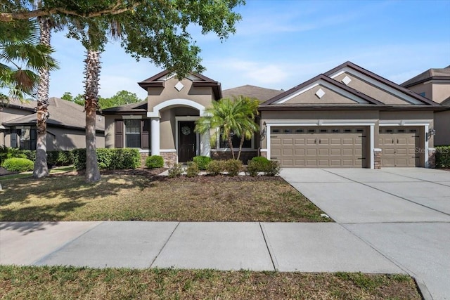 view of front of home featuring stone siding, stucco siding, a garage, and driveway