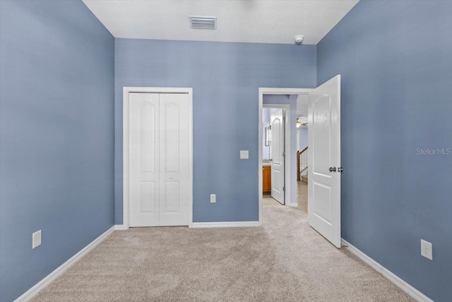 unfurnished bedroom featuring carpet flooring, a closet, visible vents, and baseboards