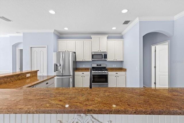 kitchen featuring ornamental molding, visible vents, white cabinetry, arched walkways, and stainless steel appliances
