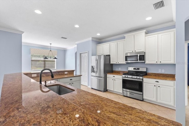 kitchen featuring ornamental molding, white cabinets, appliances with stainless steel finishes, and a sink