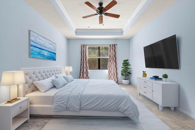 bedroom featuring a tray ceiling, a ceiling fan, and ornamental molding