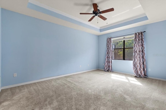 unfurnished room with ornamental molding, a raised ceiling, carpet, and a ceiling fan