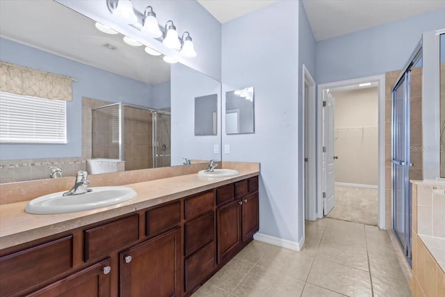 full bath with a sink, a spacious closet, a shower stall, and tile patterned floors