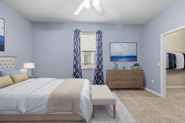 carpeted bedroom featuring a walk in closet, baseboards, a ceiling fan, and a closet