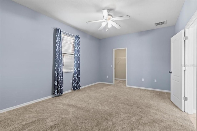 unfurnished bedroom with a ceiling fan, baseboards, visible vents, a spacious closet, and light colored carpet