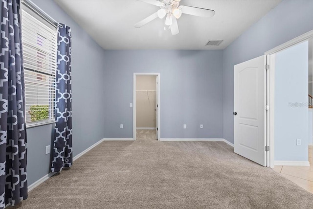 unfurnished bedroom with ceiling fan, carpet flooring, visible vents, and a walk in closet