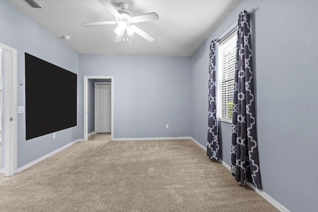 spare room featuring light colored carpet, visible vents, baseboards, and ceiling fan