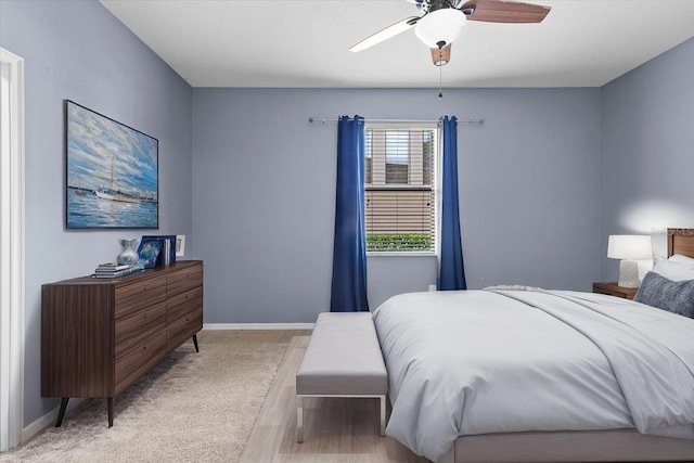 bedroom with light carpet, baseboards, and a ceiling fan