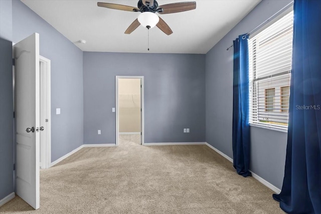 unfurnished bedroom featuring a walk in closet, carpet flooring, and baseboards