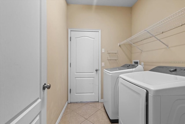 washroom with separate washer and dryer, laundry area, light tile patterned floors, and baseboards