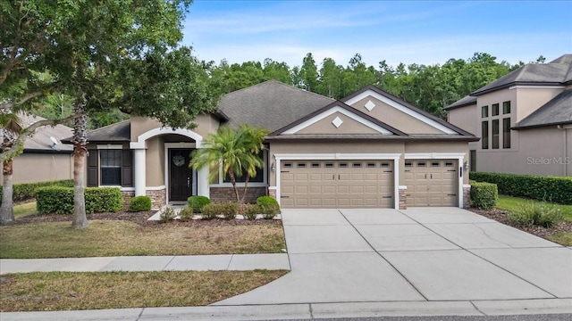 view of front of home featuring an attached garage, stucco siding, stone siding, and driveway