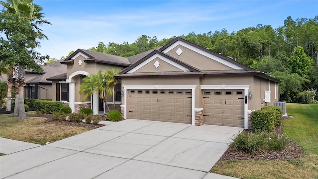 view of front facade with stone siding, an attached garage, stucco siding, central AC unit, and driveway