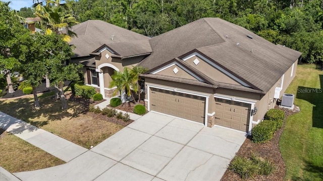 view of front facade with concrete driveway, stone siding, stucco siding, and an attached garage