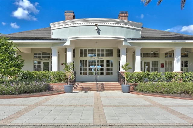 entrance to property with stucco siding, covered porch, and a chimney