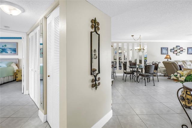 6011 Bahia Del Mar Blvd Unit 158, Saint Petersburg, FL 33715 - corridor featuring a textured ceiling, light tile patterned flooring, baseboards, and a chandelier
