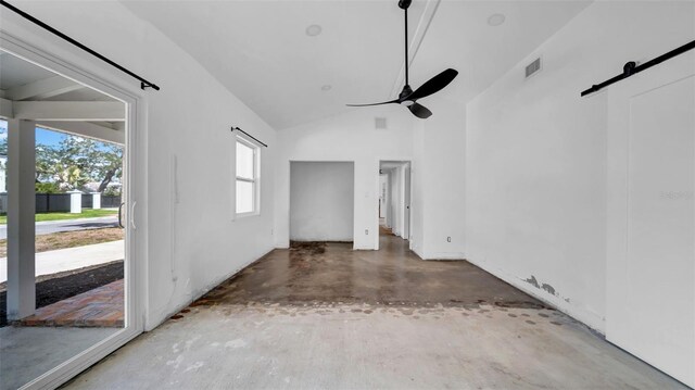 unfurnished living room with ceiling fan, visible vents, concrete flooring, a barn door, and lofted ceiling