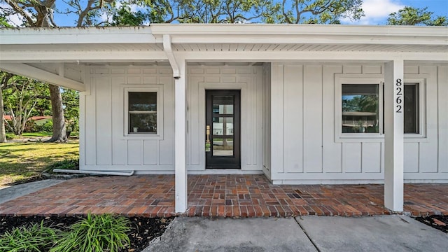 view of exterior entry featuring board and batten siding and a porch