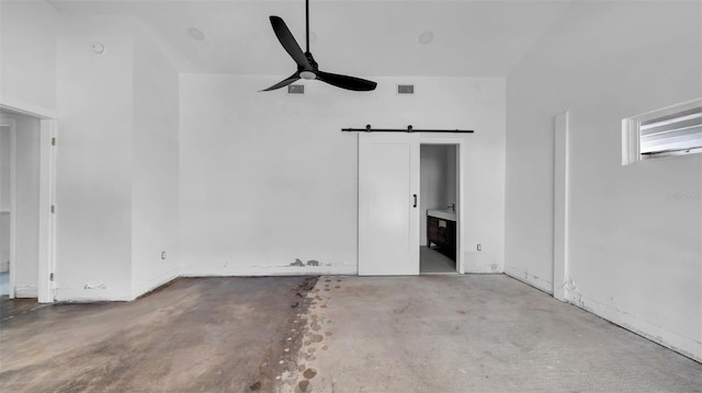 interior space with visible vents, a barn door, concrete flooring, and a ceiling fan