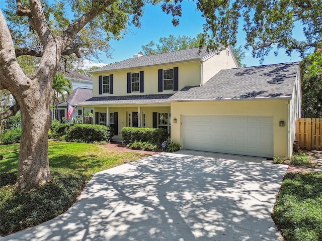 traditional home with fence, an attached garage, driveway, stucco siding, and a front lawn