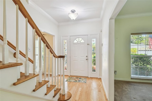 foyer entrance with a wealth of natural light, ornamental molding, and stairs