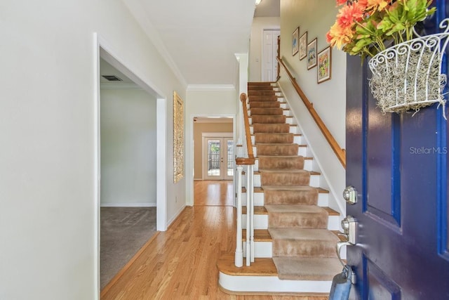 entrance foyer featuring wood finished floors, ornamental molding, visible vents, stairway, and baseboards