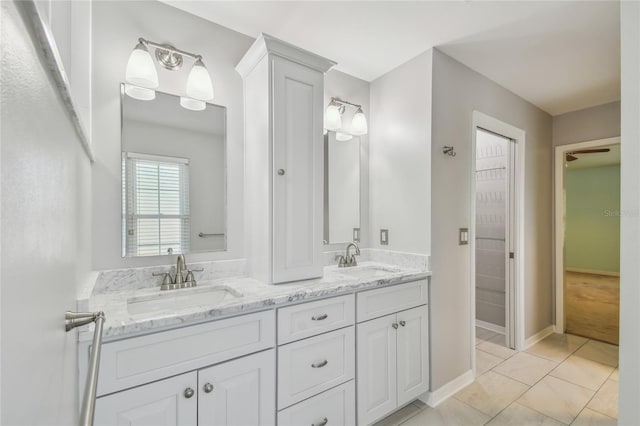 bathroom featuring tile patterned floors, double vanity, baseboards, and a sink
