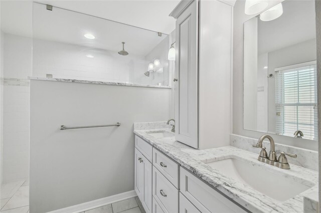 bathroom featuring recessed lighting, double vanity, a tile shower, and a sink