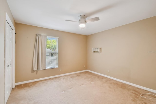 spare room featuring light carpet, baseboards, a ceiling fan, and a wall unit AC
