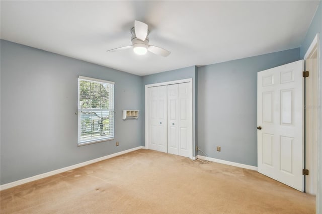 unfurnished bedroom featuring a closet, light carpet, baseboards, and a ceiling fan