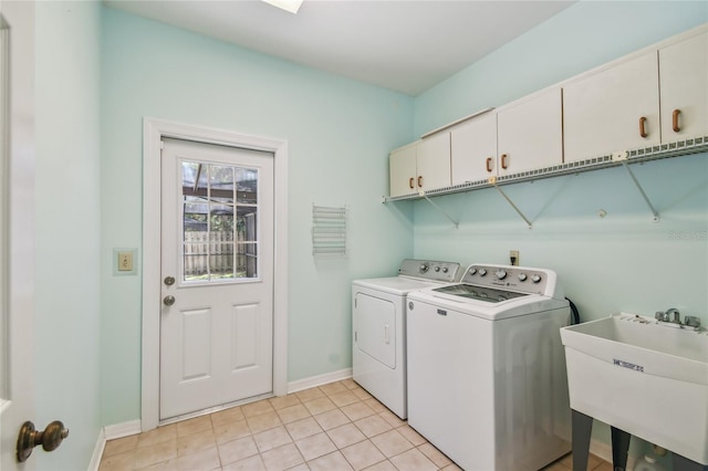 laundry area with a sink, cabinet space, light tile patterned flooring, washing machine and dryer, and baseboards