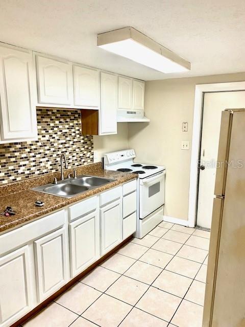 kitchen featuring a sink, under cabinet range hood, backsplash, white appliances, and white cabinets
