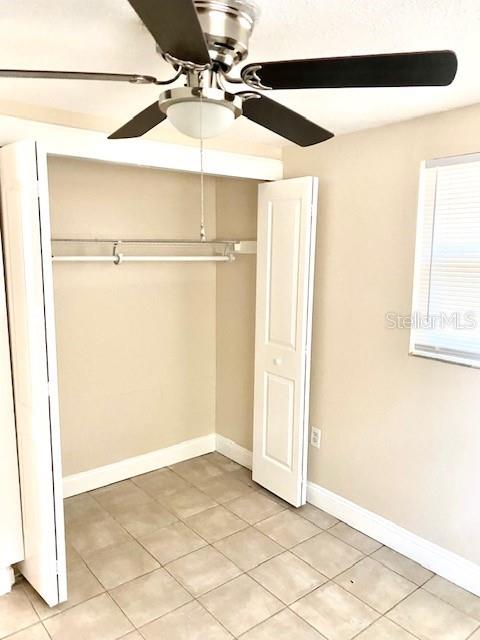 unfurnished bedroom featuring light tile patterned flooring, a closet, ceiling fan, and baseboards
