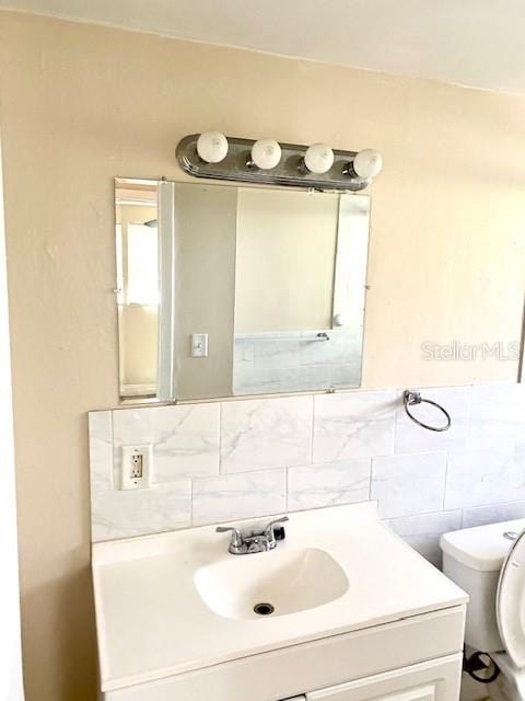 bathroom with toilet, vanity, and tile walls