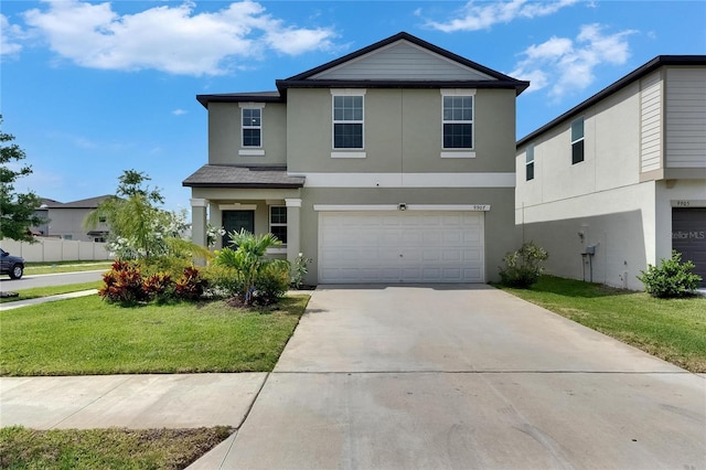 view of front of property with an attached garage, driveway, a front lawn, and stucco siding