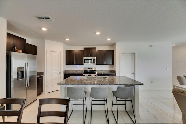 kitchen with visible vents, a kitchen breakfast bar, dark brown cabinetry, and stainless steel appliances