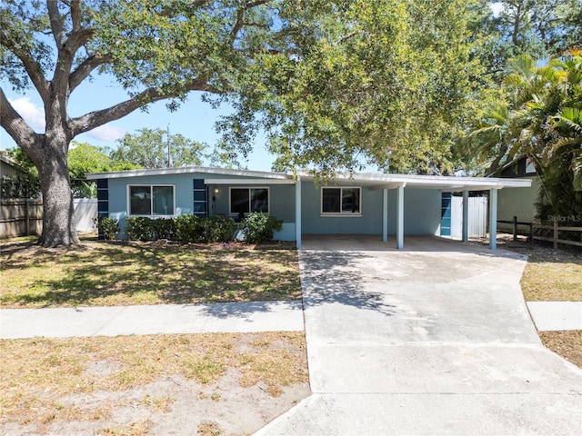ranch-style house featuring fence, a carport, stucco siding, and driveway