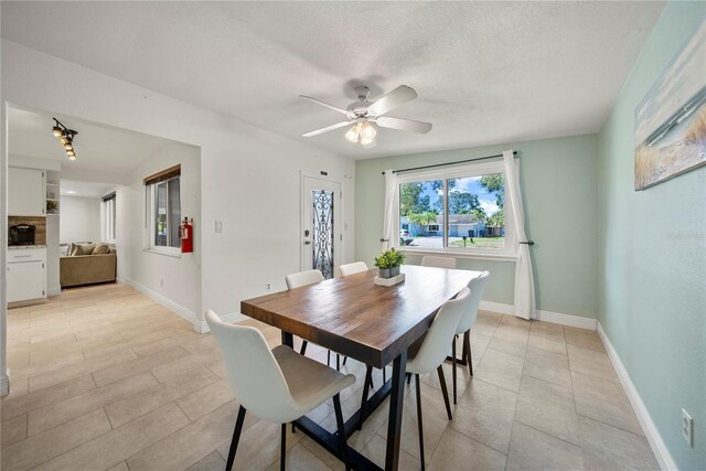 dining area with baseboards, a ceiling fan, a textured ceiling, and light tile patterned floors