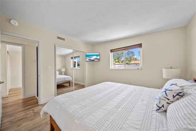 bedroom with baseboards, a closet, light wood-type flooring, and visible vents
