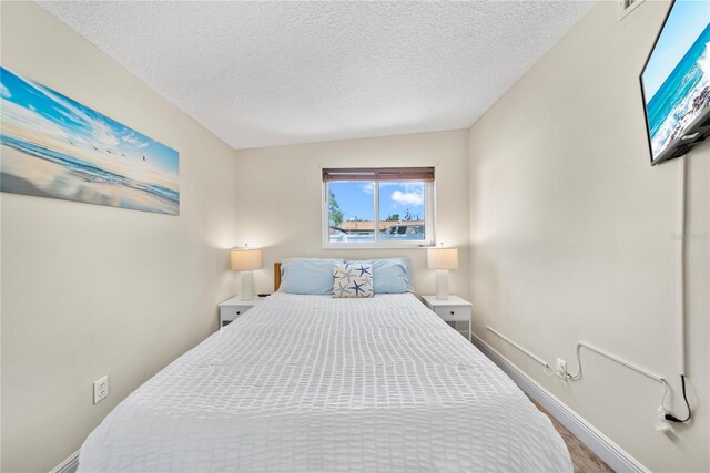 bedroom featuring a textured ceiling, baseboards, and wood finished floors