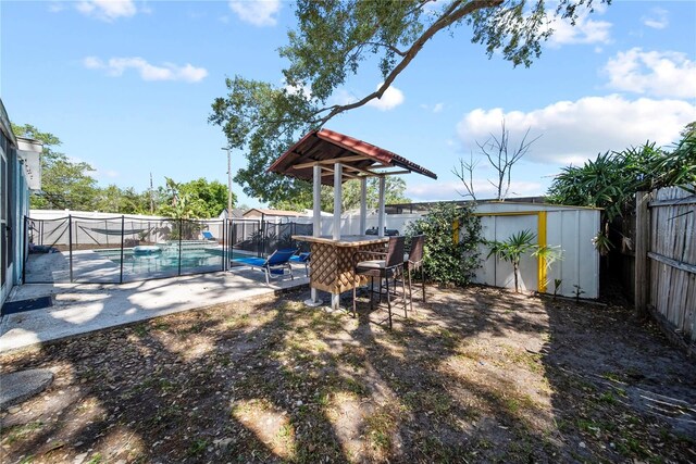 view of yard featuring a storage unit, a fenced backyard, a patio area, and a fenced in pool