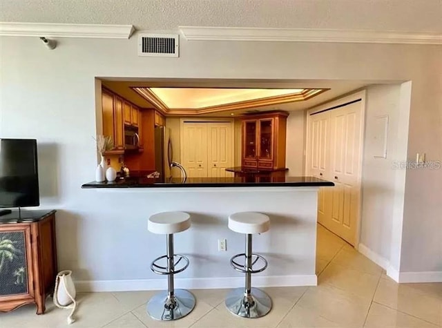 bar with crown molding, a raised ceiling, stainless steel appliances, and visible vents