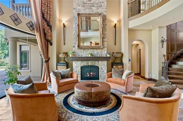 1102 Merry Water Dr, Lutz, FL 33548 - living area featuring stone tile floors, a towering ceiling, a warm lit fireplace, stairway, and arched walkways