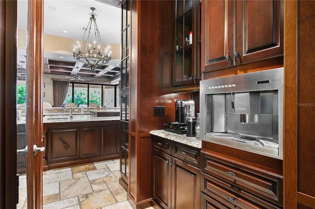 1102 Merry Water Dr, Lutz, FL 33548 - kitchen featuring a sink, light stone counters, a notable chandelier, coffered ceiling, and stone tile floors