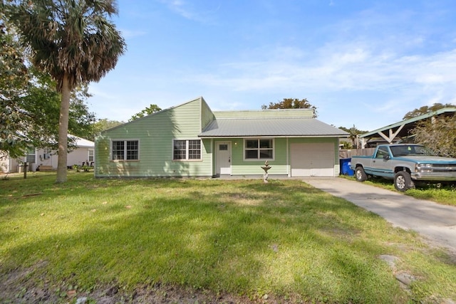 ranch-style house with a front yard, concrete driveway, metal roof, and a garage